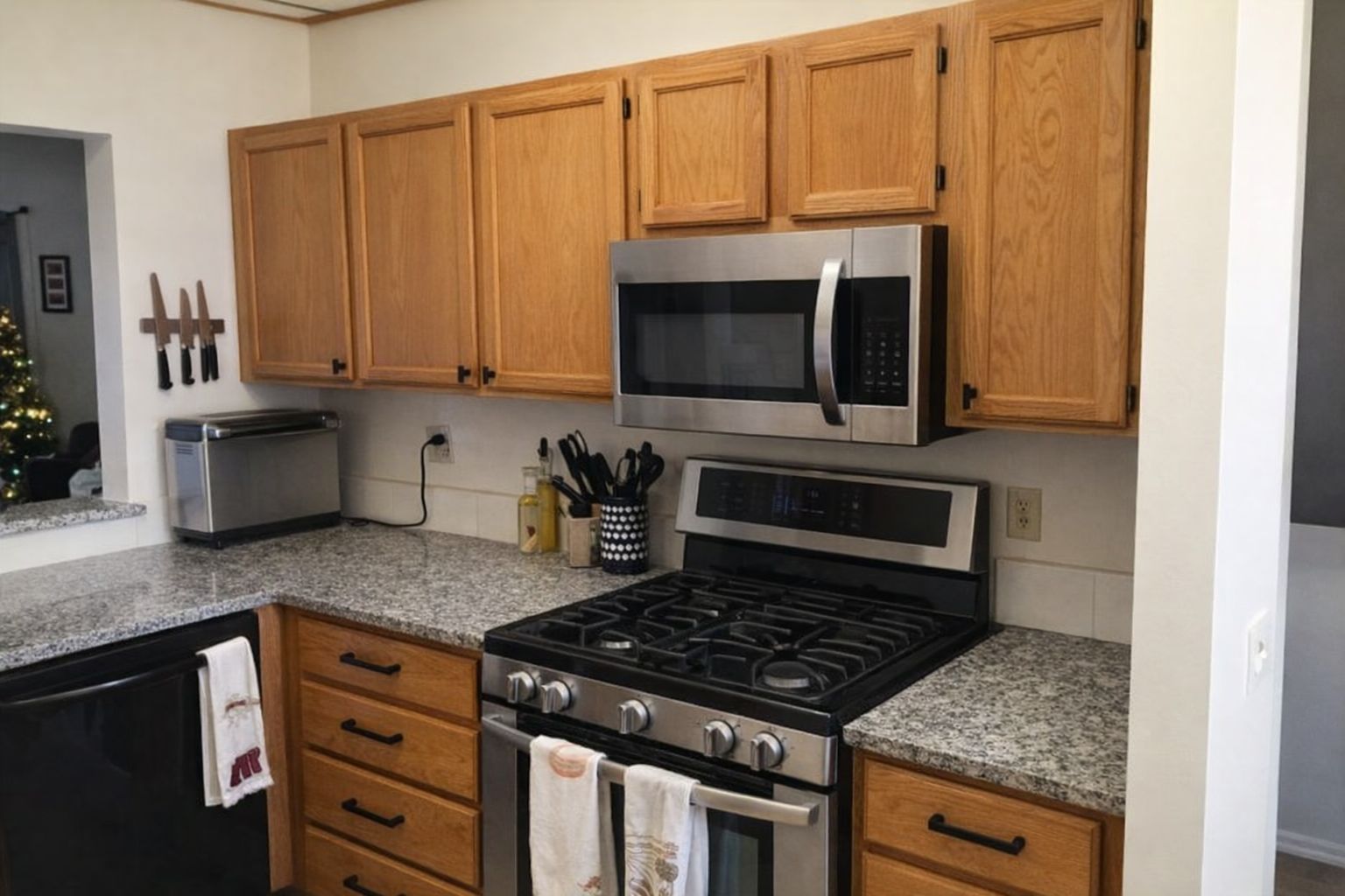 Kjøkken med eikeskap og moderne sorte håndtak på skuffer og dører.